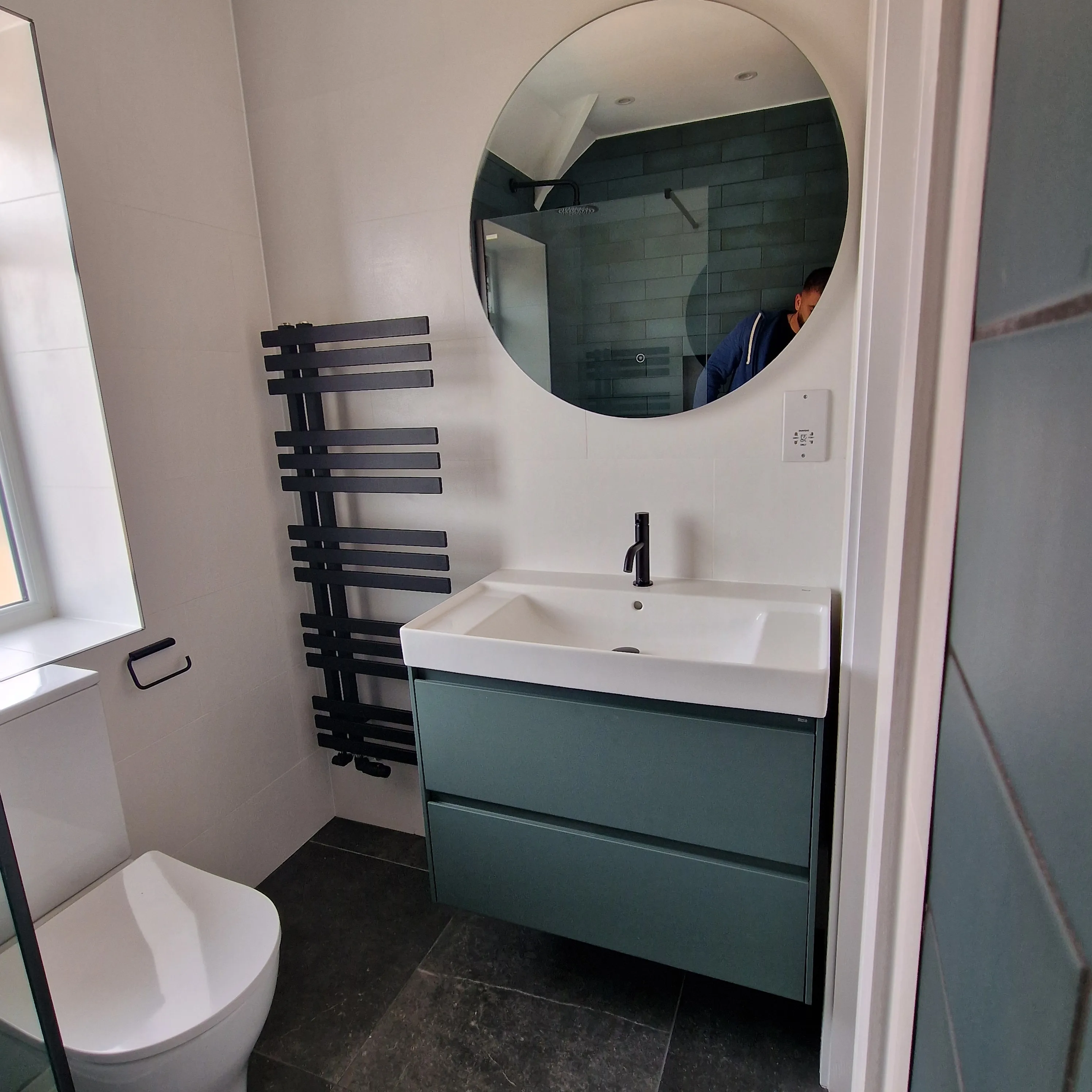 Modern bathroom featuring a round mirror, sleek sink, and stylish storage