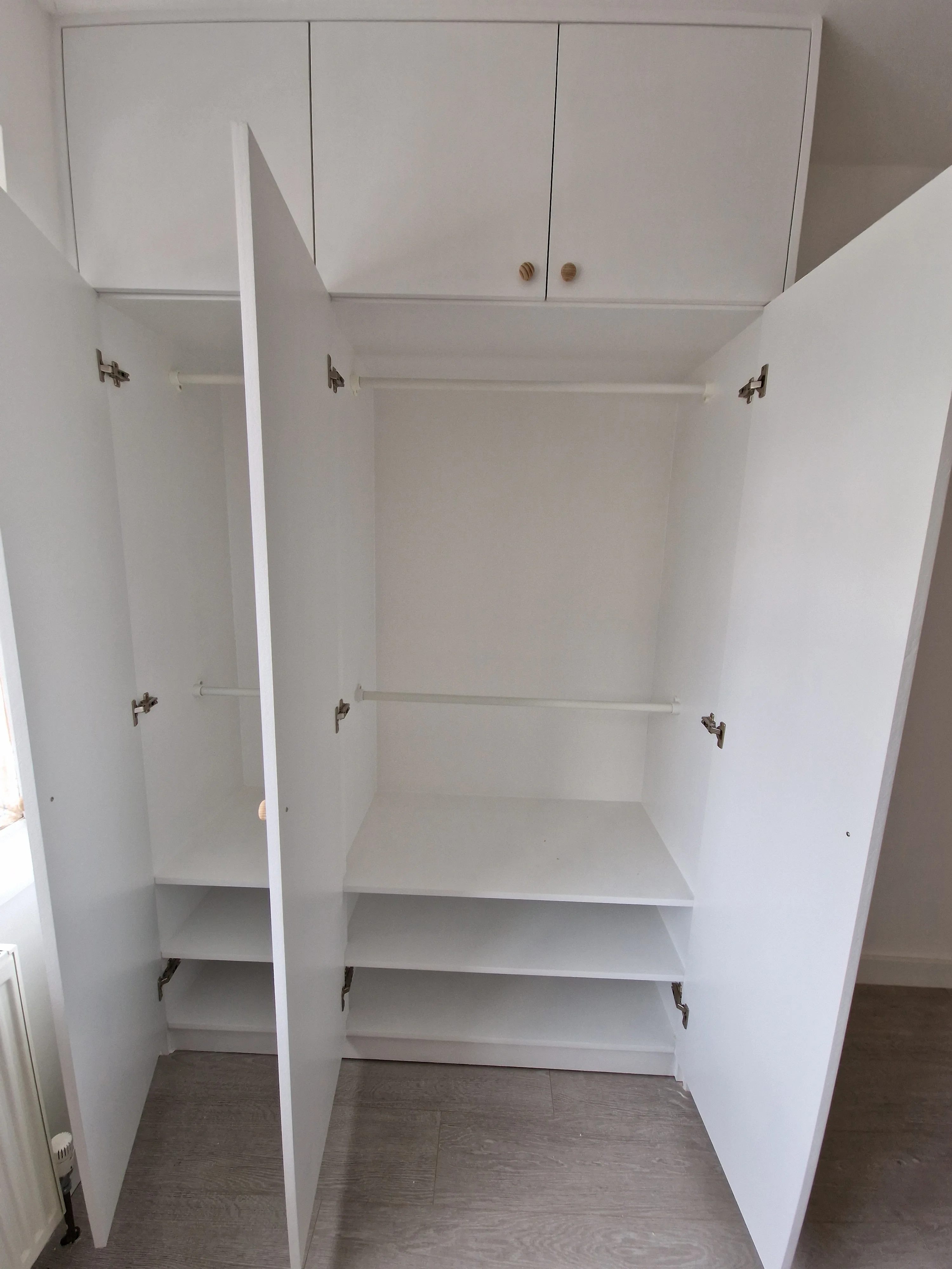 Empty bespoke wardrobe with open doors, showcasing interior shelving and clean design