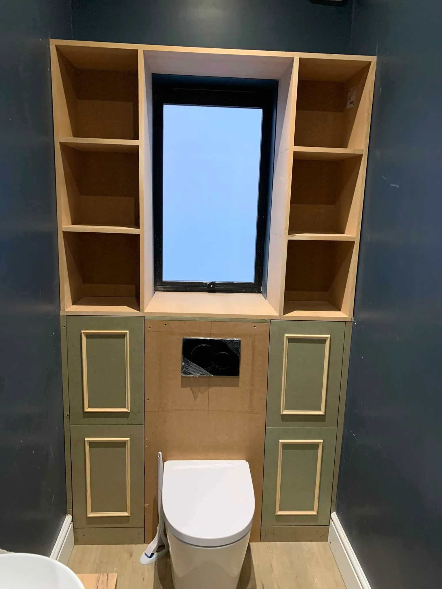 Bathroom renovation in progress with custom cabinetry and window framing