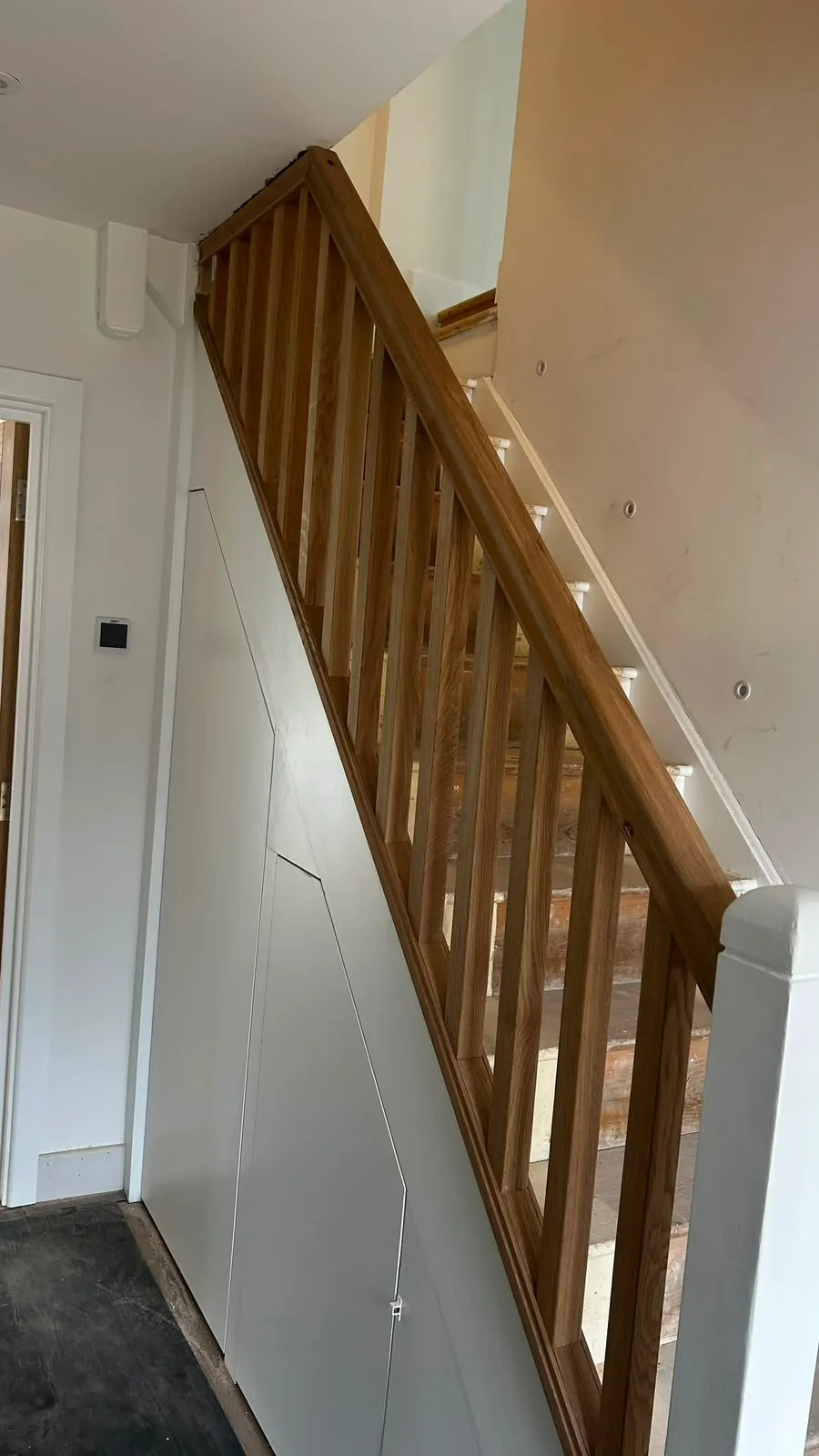Wooden staircase with modern design and white walls, showcasing craftsmanship in home refurbishment