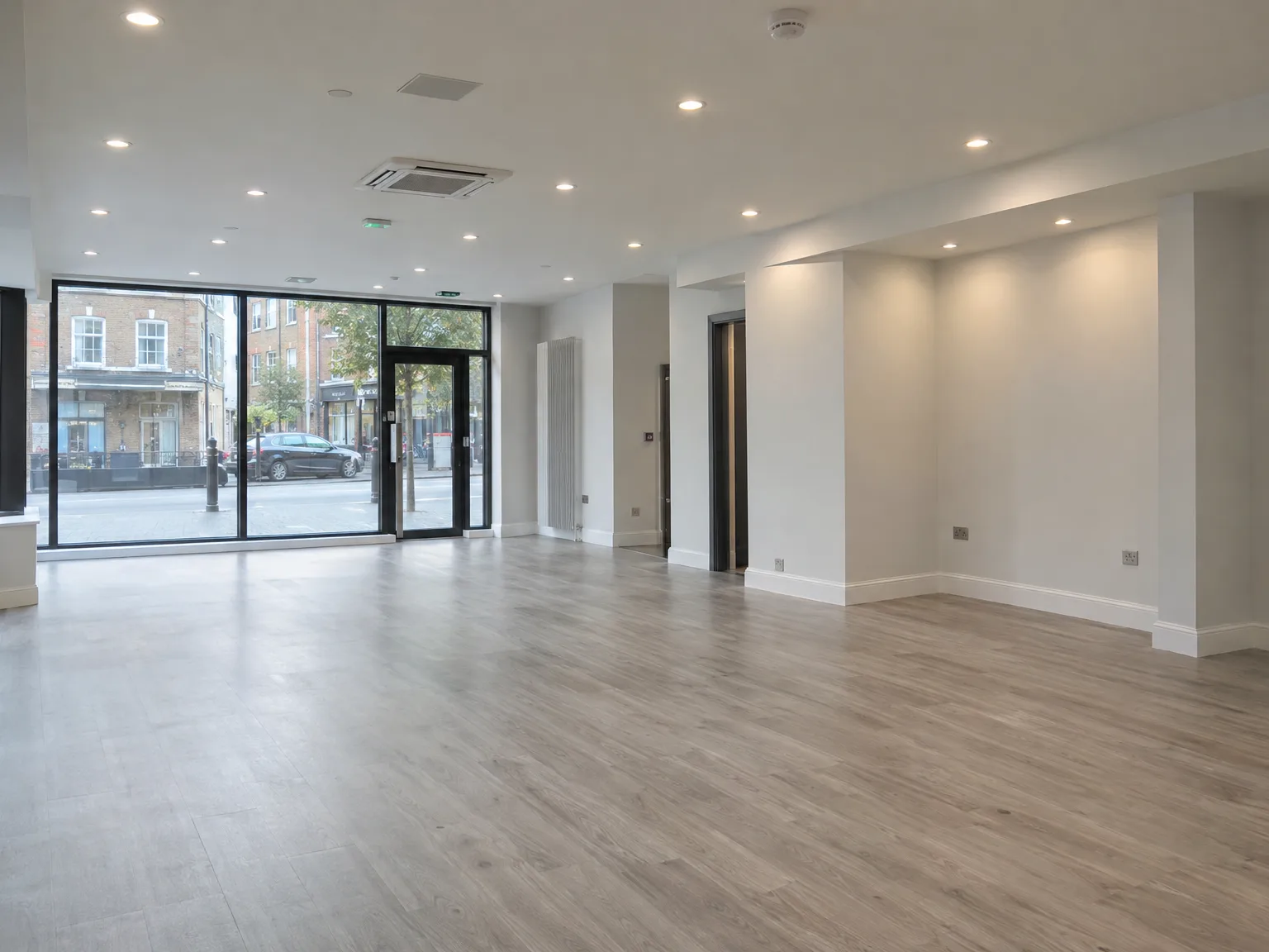 Newly renovated commercial interior featuring mixed flooring, large storefront glazing, and modern recessed ceiling lighting