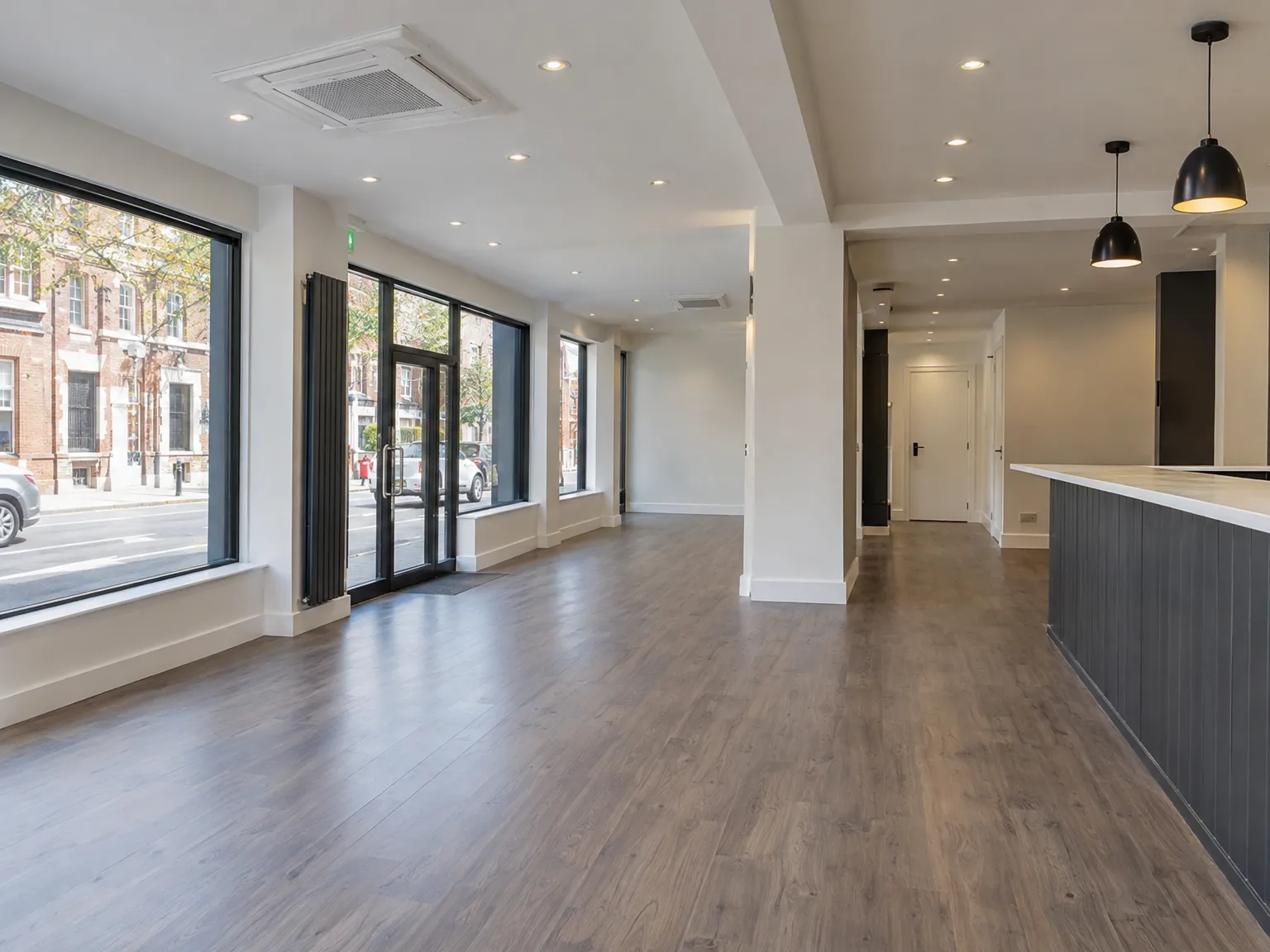 Renovated interior with wooden floor, white walls, and contemporary pendant lighting