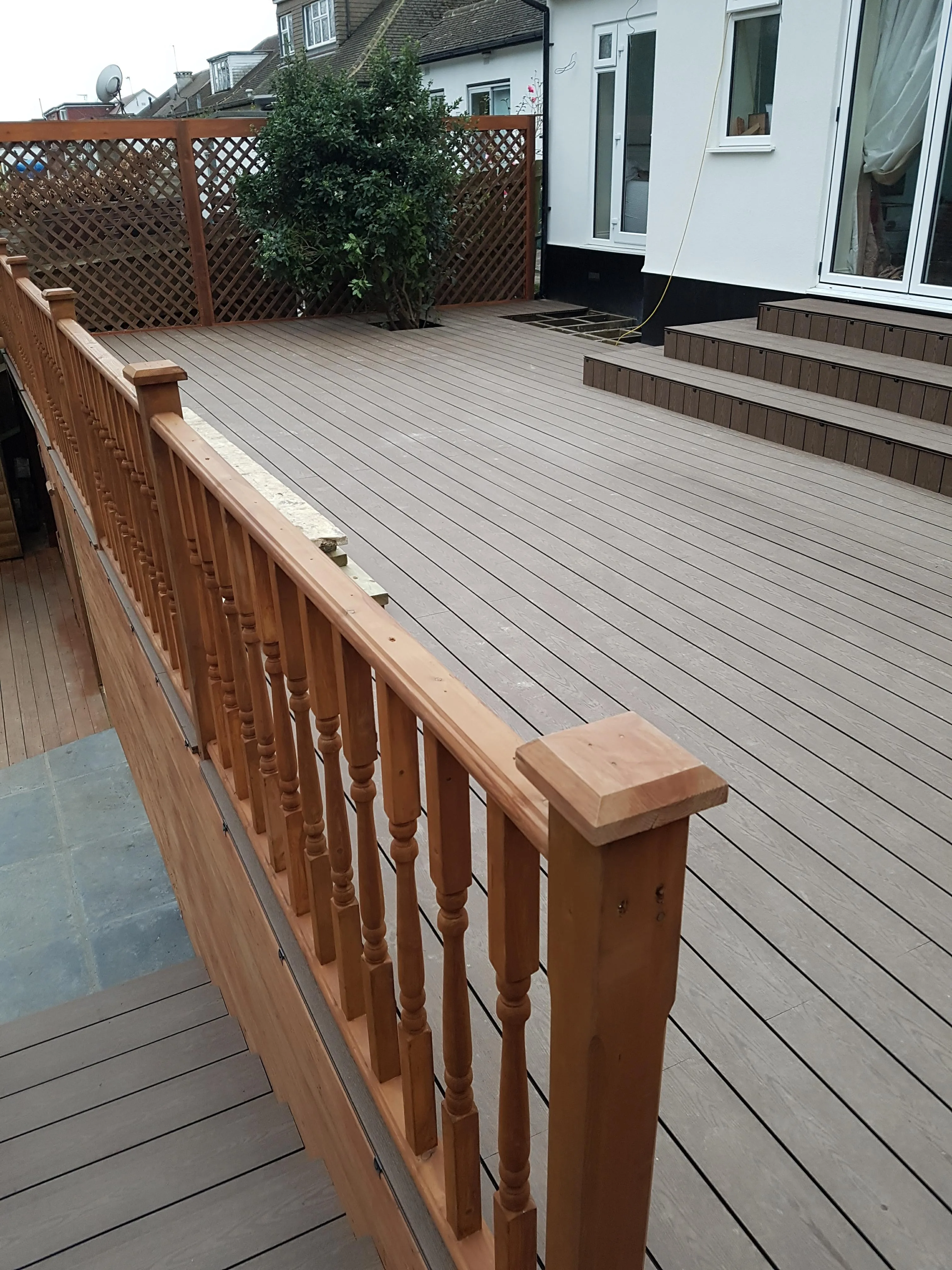 A wooden decking area with a railing and steps leading to a house, ideal for outdoor renovations