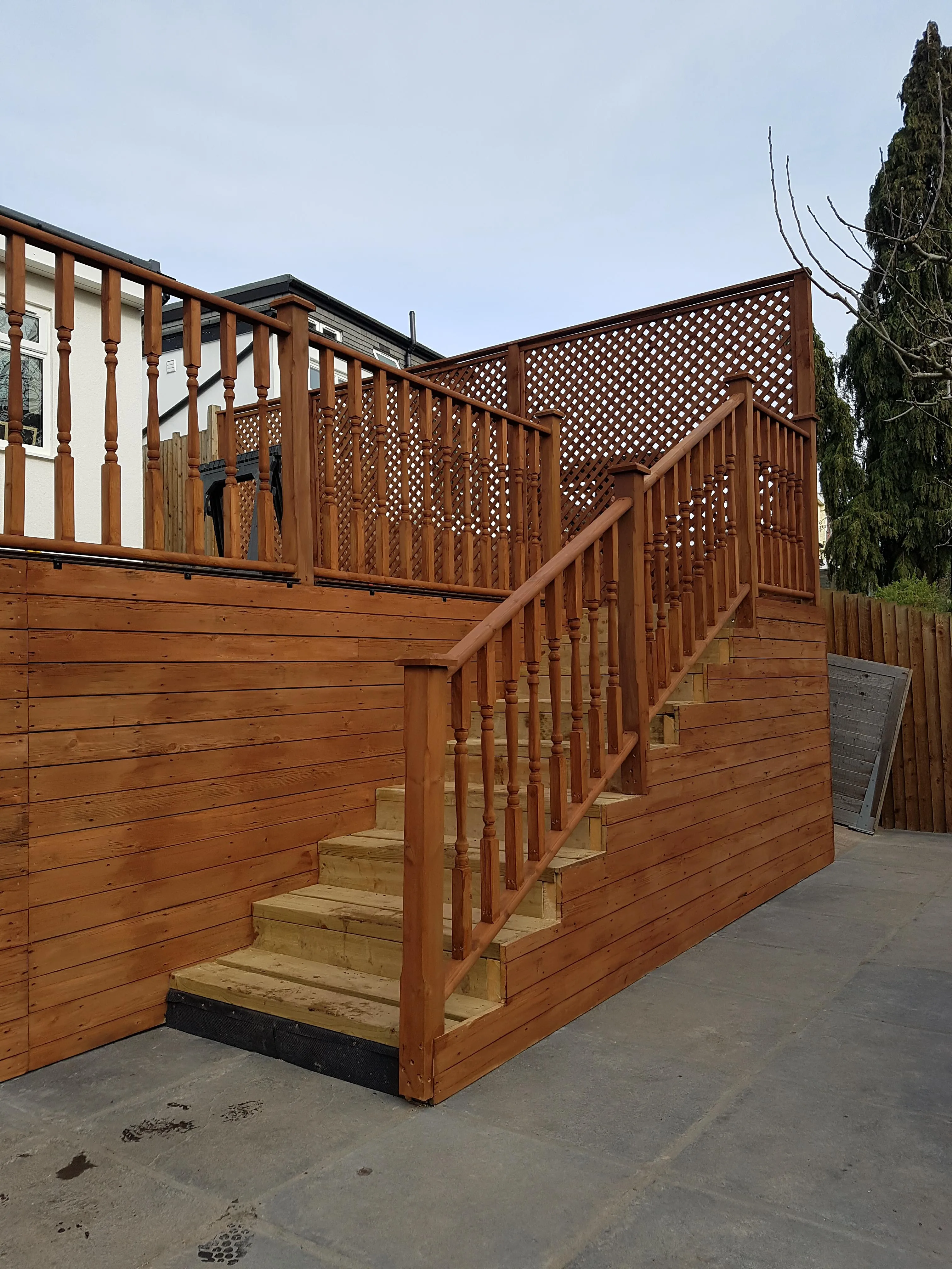 Newly built wooden staircase with decorative railing and surrounding decking