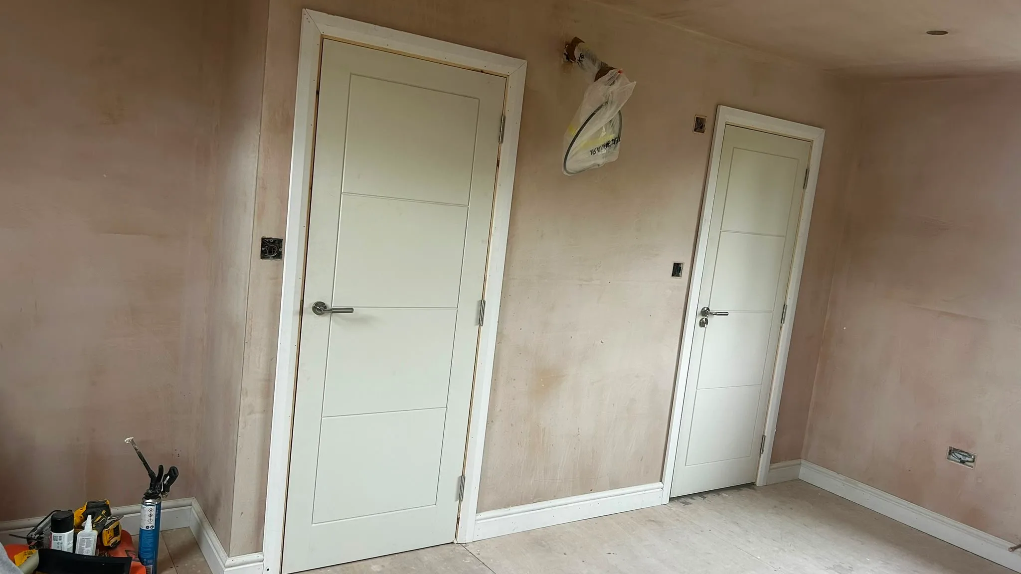 Interior view of a room showcasing newly installed doors with unfinished walls, indicating a renovation project
