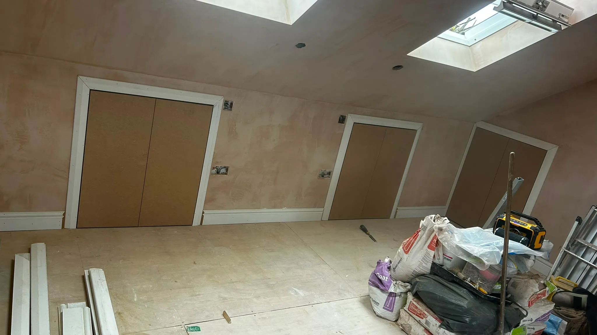Interior view of a loft conversion with three boarded doors and unfinished walls