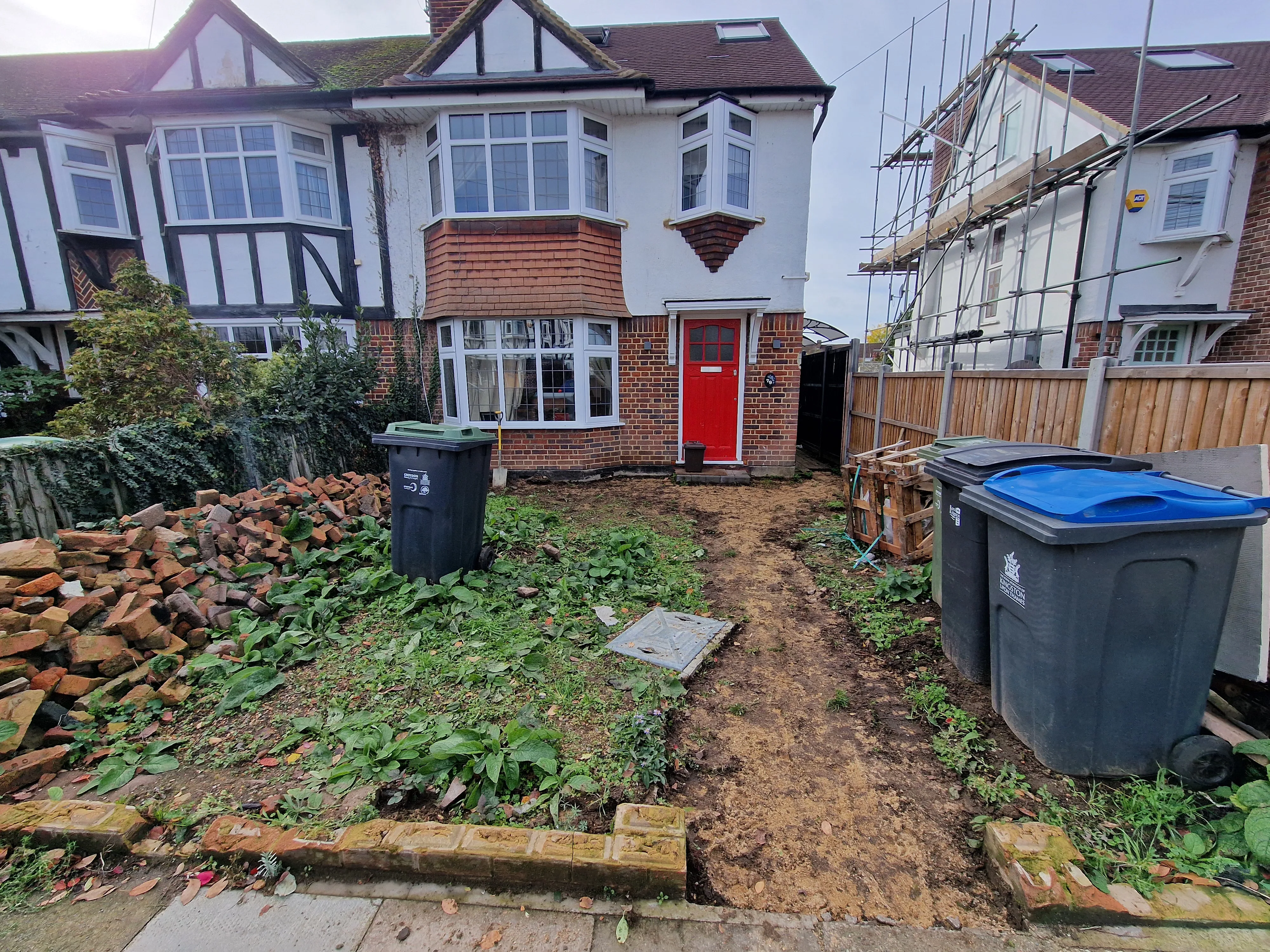 Front garden area with construction materials and bins, indicating property refurbishment service