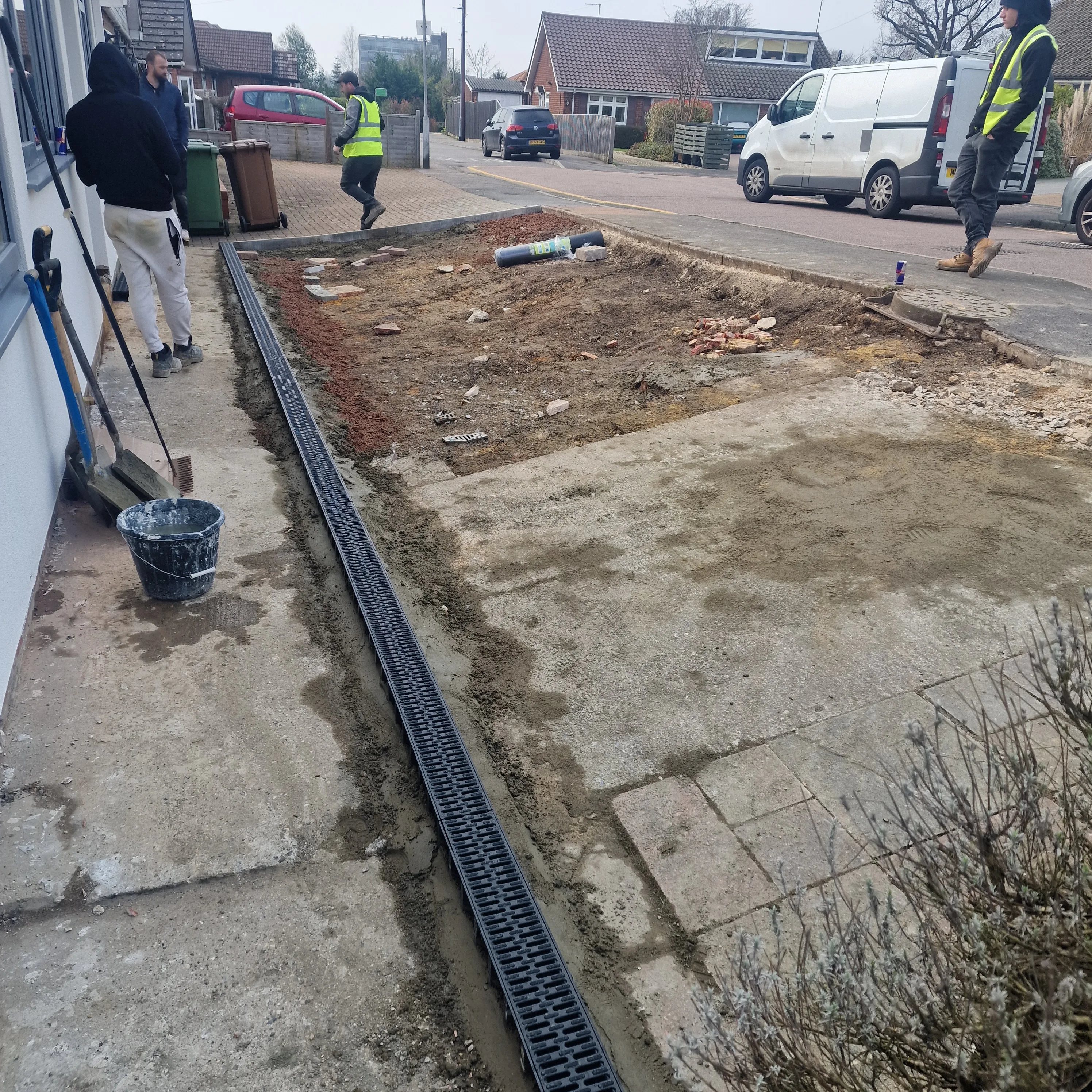 Workers installing drainage and preparing a driveway at a residential property