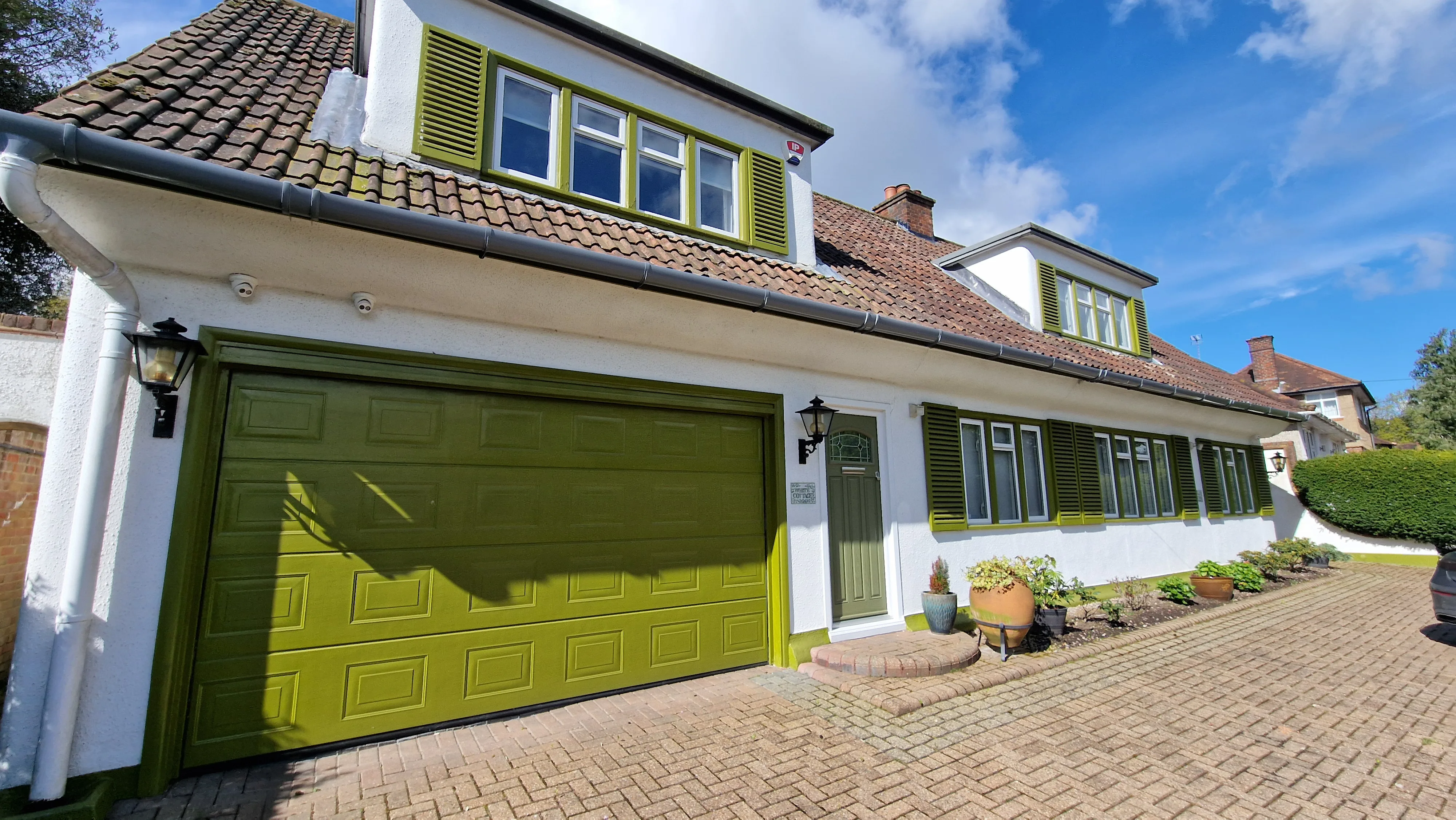 Front view of a renovated house featuring green shutters and garage door