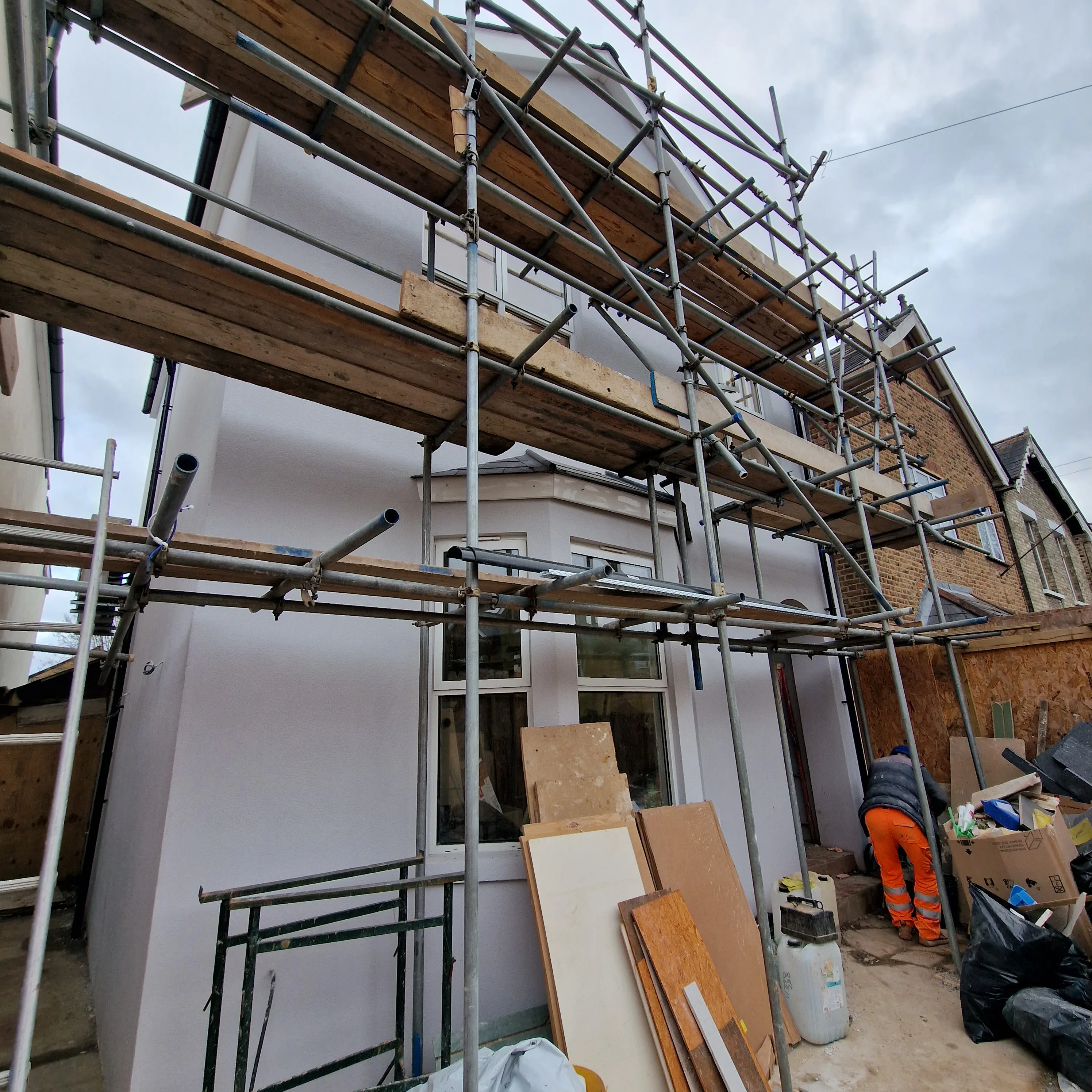 House exterior undergoing rendering with scaffolding and construction materials visible