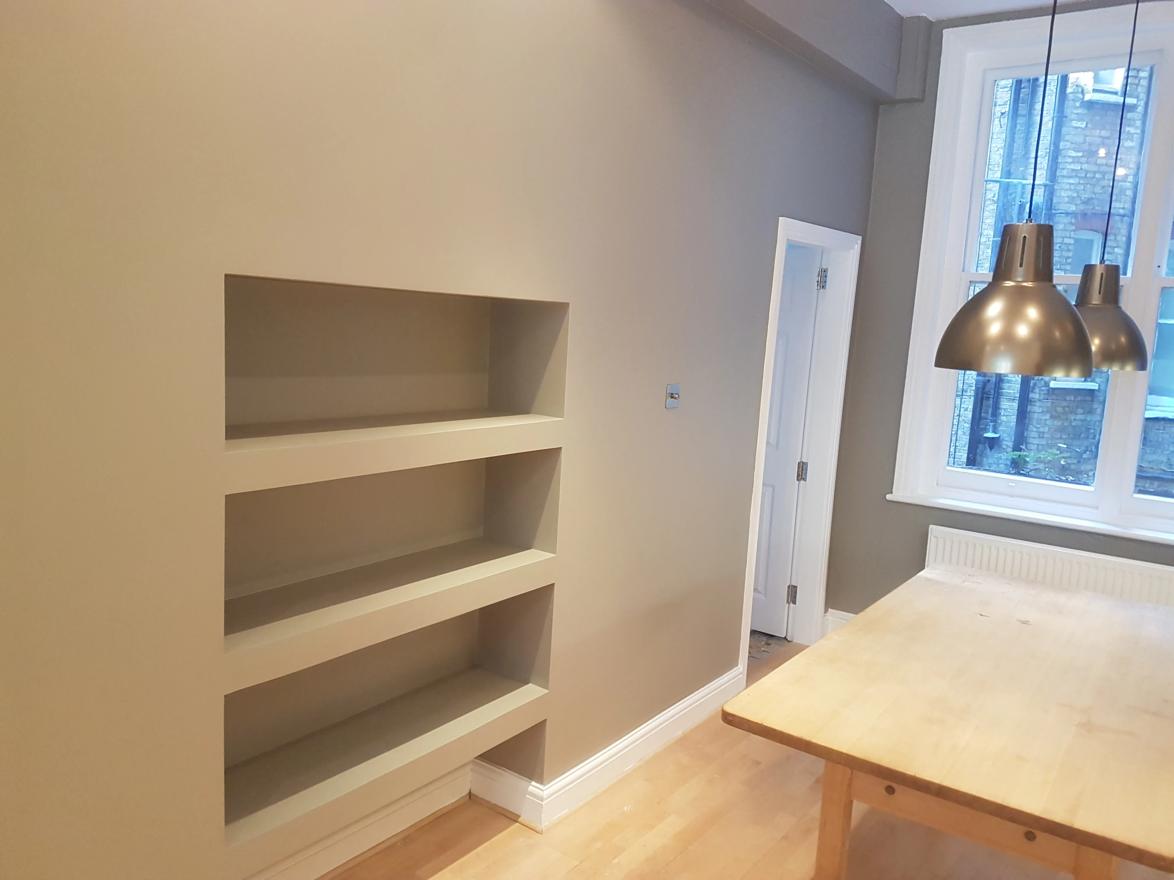 Interior view of a modern kitchen with built-in shelves and pendant lights