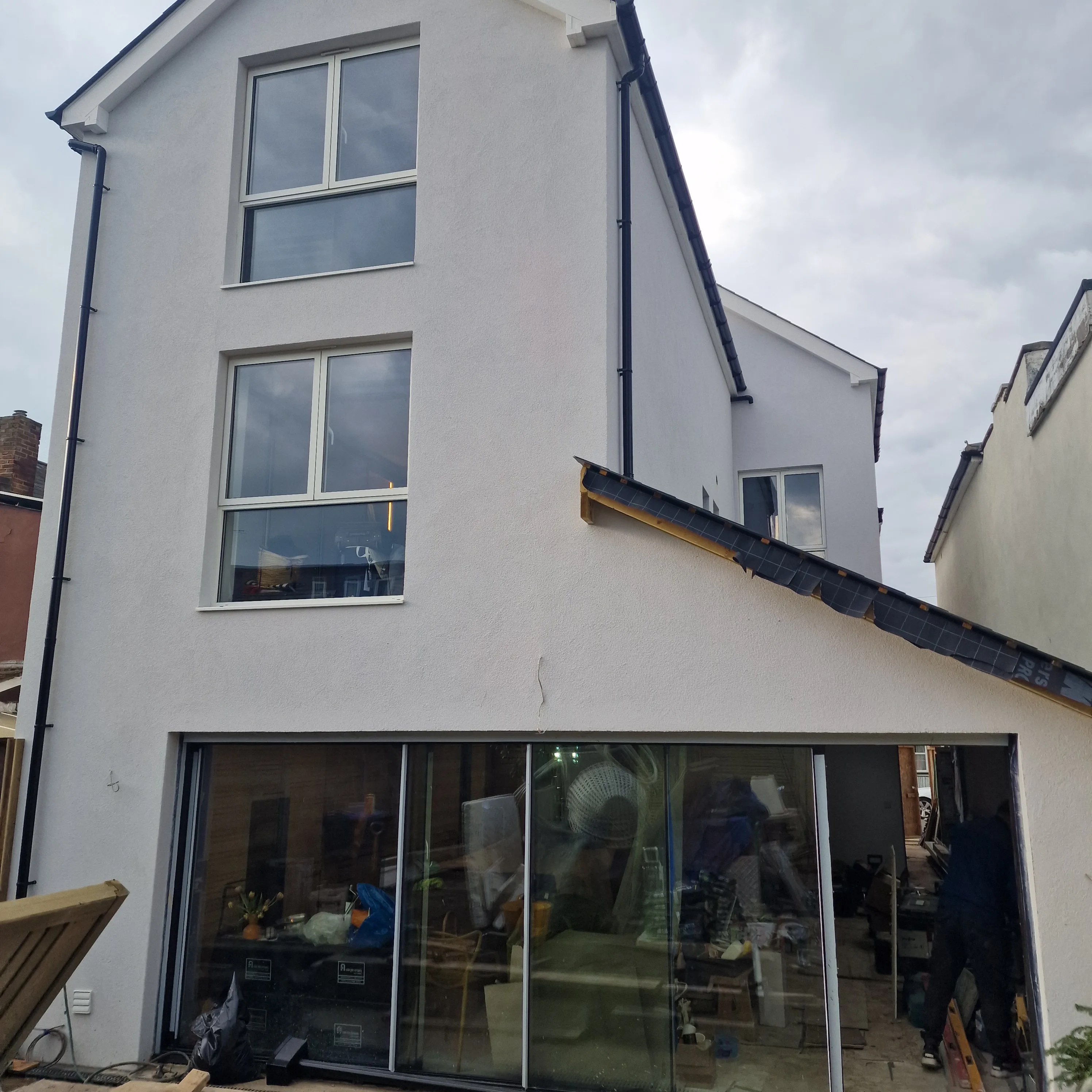 Modern house renovation showcasing a freshly rendered exterior with large glass doors
