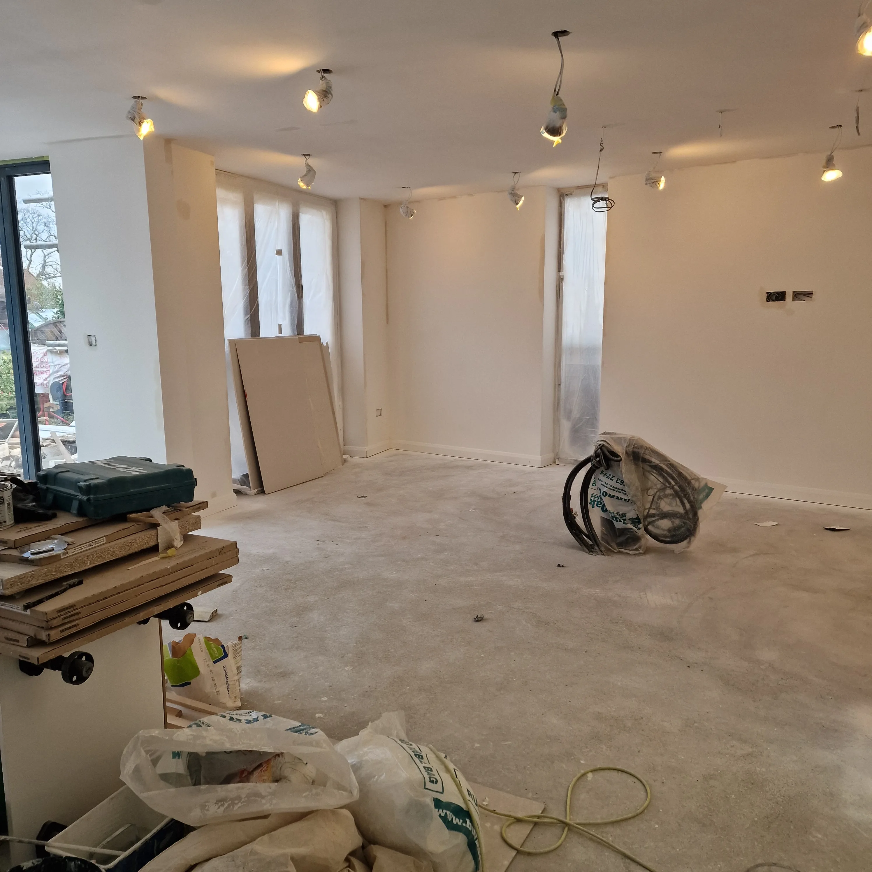 Interior during a home refurbishment showing walls under preparation and construction materials