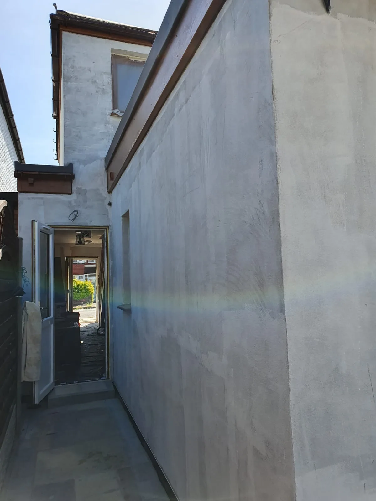 Exterior view of a freshly rendered wall showing preparation for house renovation