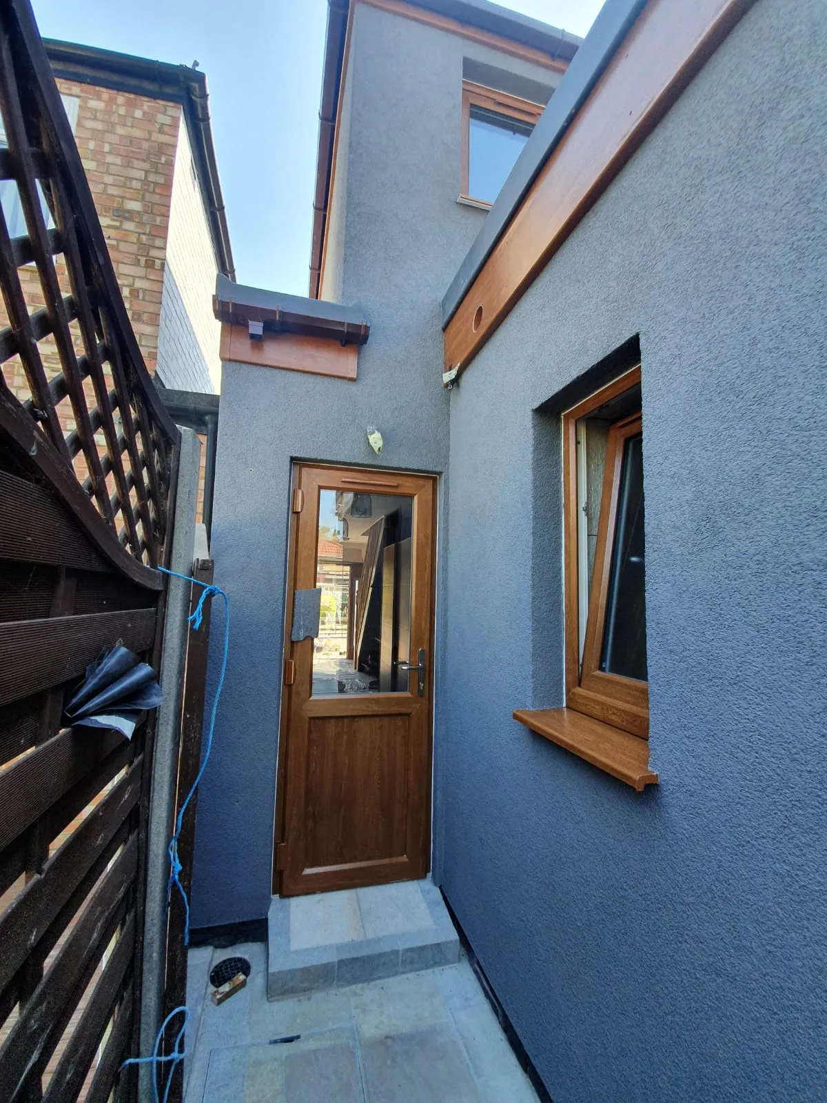 Side view of a newly renovated entrance with wooden door and grey exterior wall