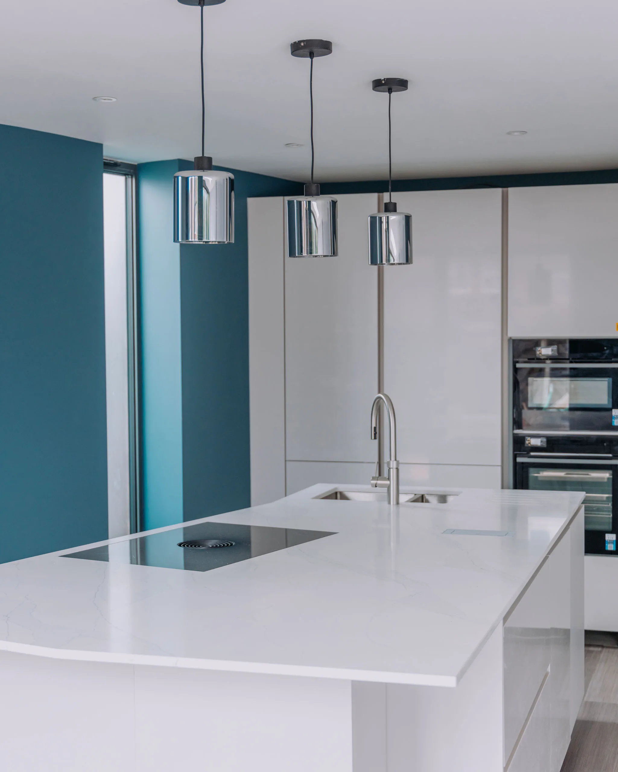 Modern kitchen refurbishment with white countertops and stylish light fixtures