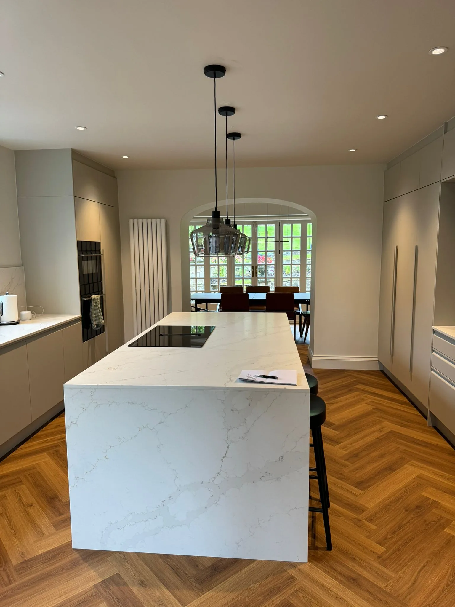 Modern kitchen design featuring a stylish island and herringbone wooden floor