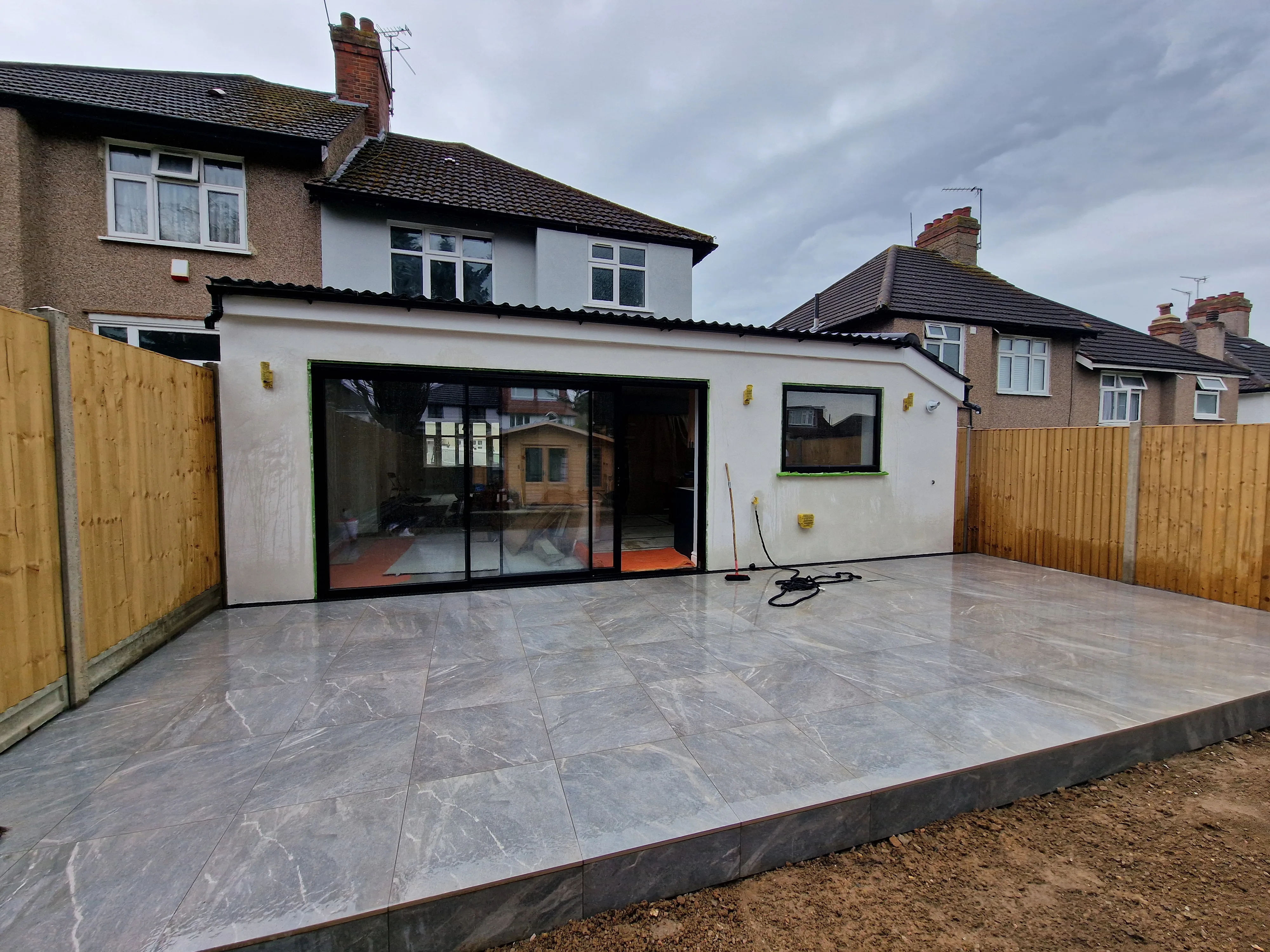 Rear view of a modern house extension with large sliding glass doors and tiled patio