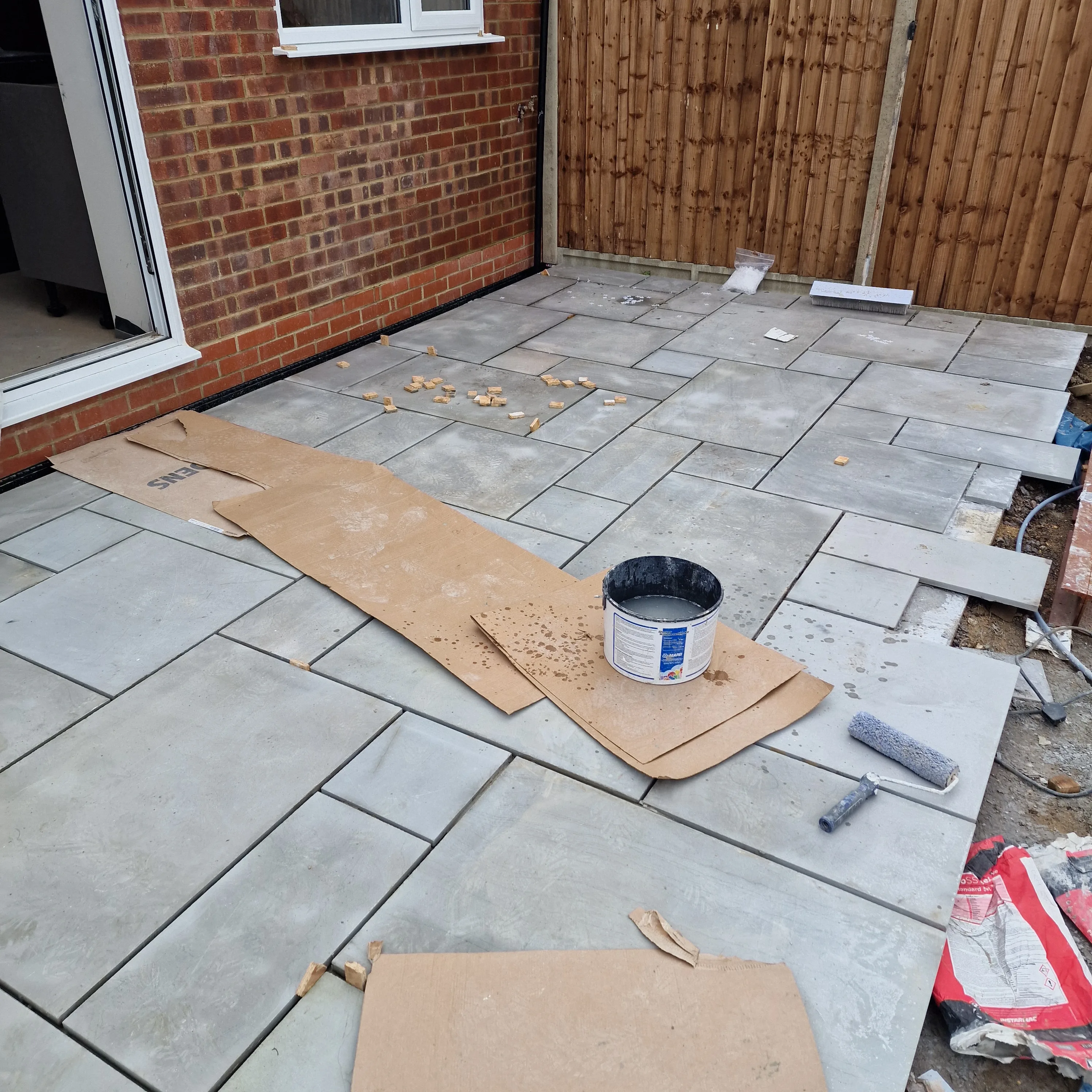 Newly laid patio with large tiles and tools for finishing touches