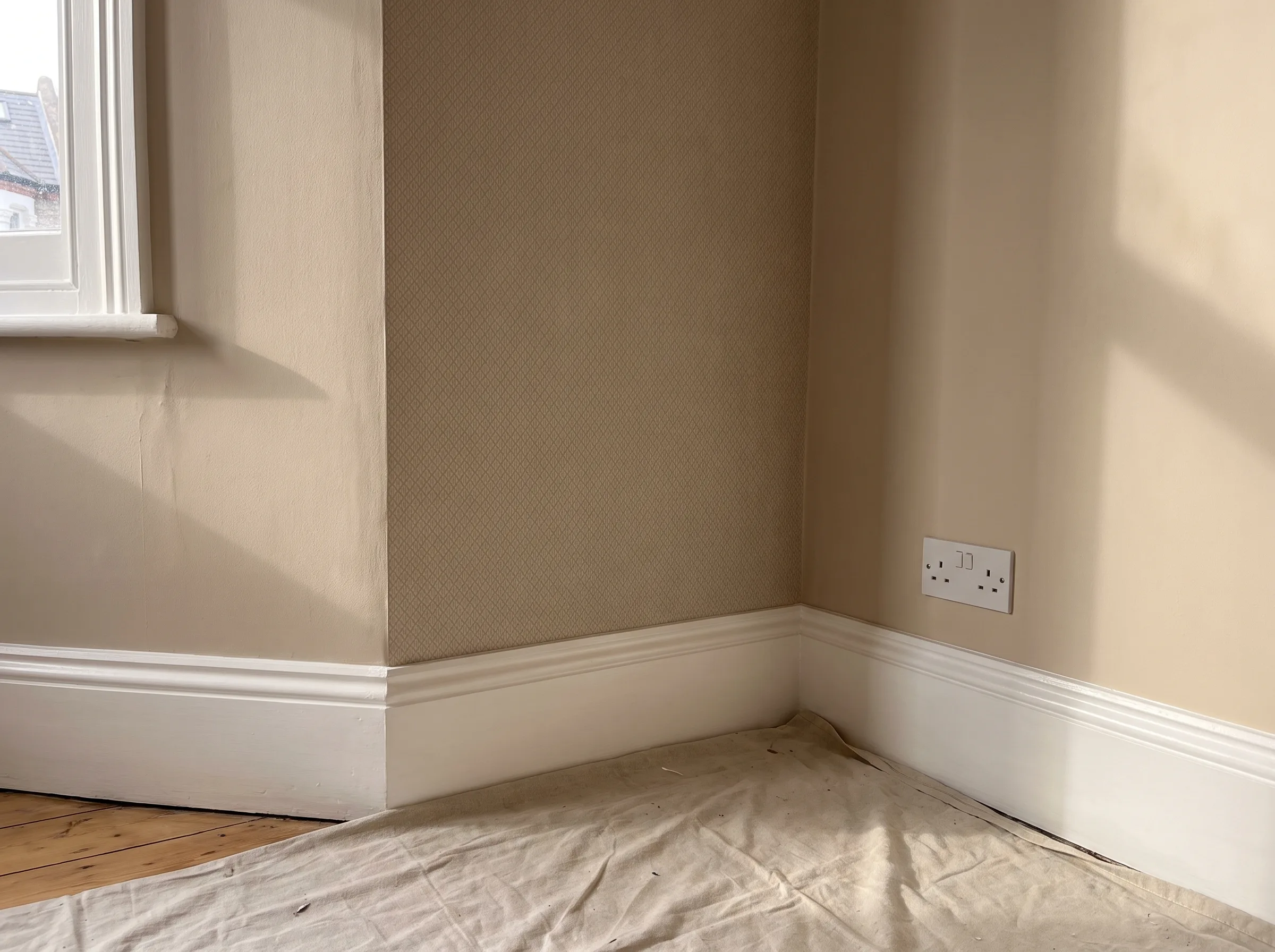 A corner of a room showing freshly painted walls and electrical outlets, indicative of interior painting services
