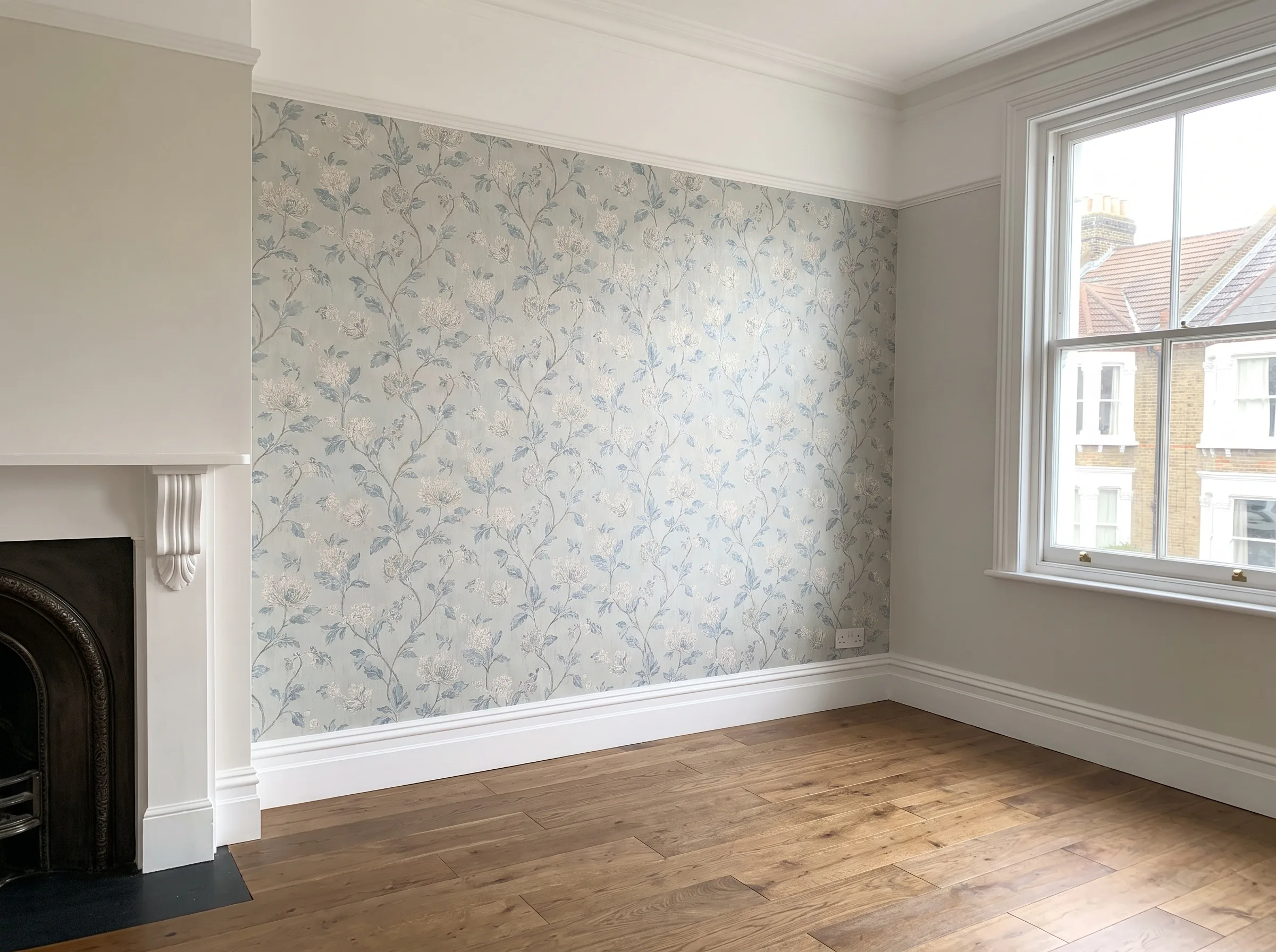 Newly wallpapered room with floral design and wooden flooring, showcasing interior painting service