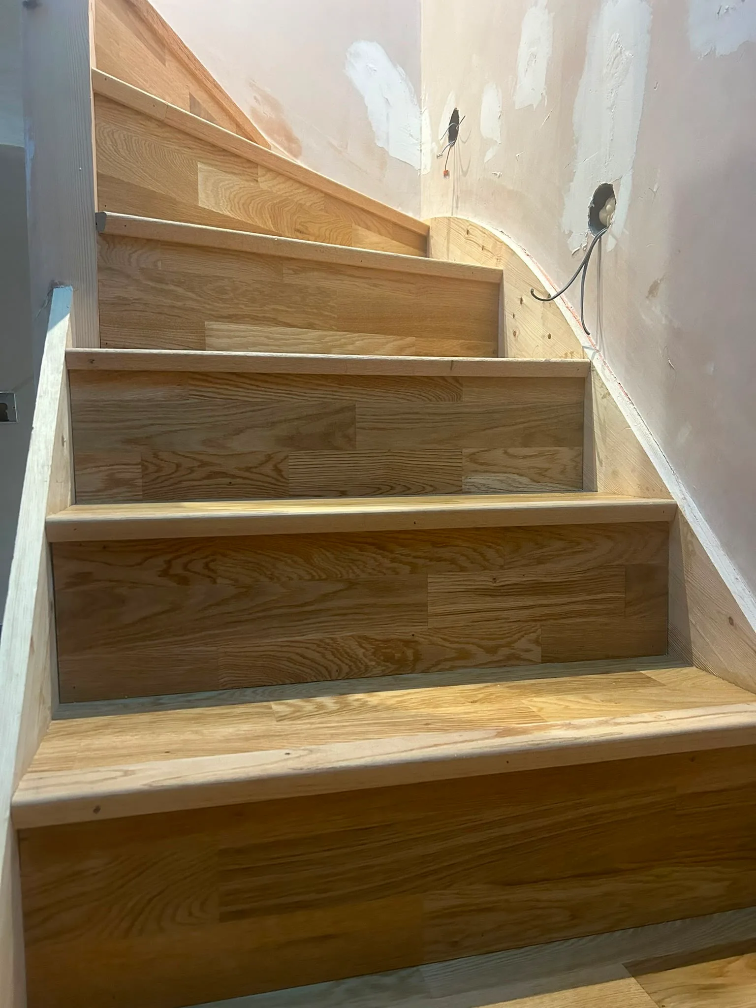 Wooden staircase showing newly installed steps and unfinished walls