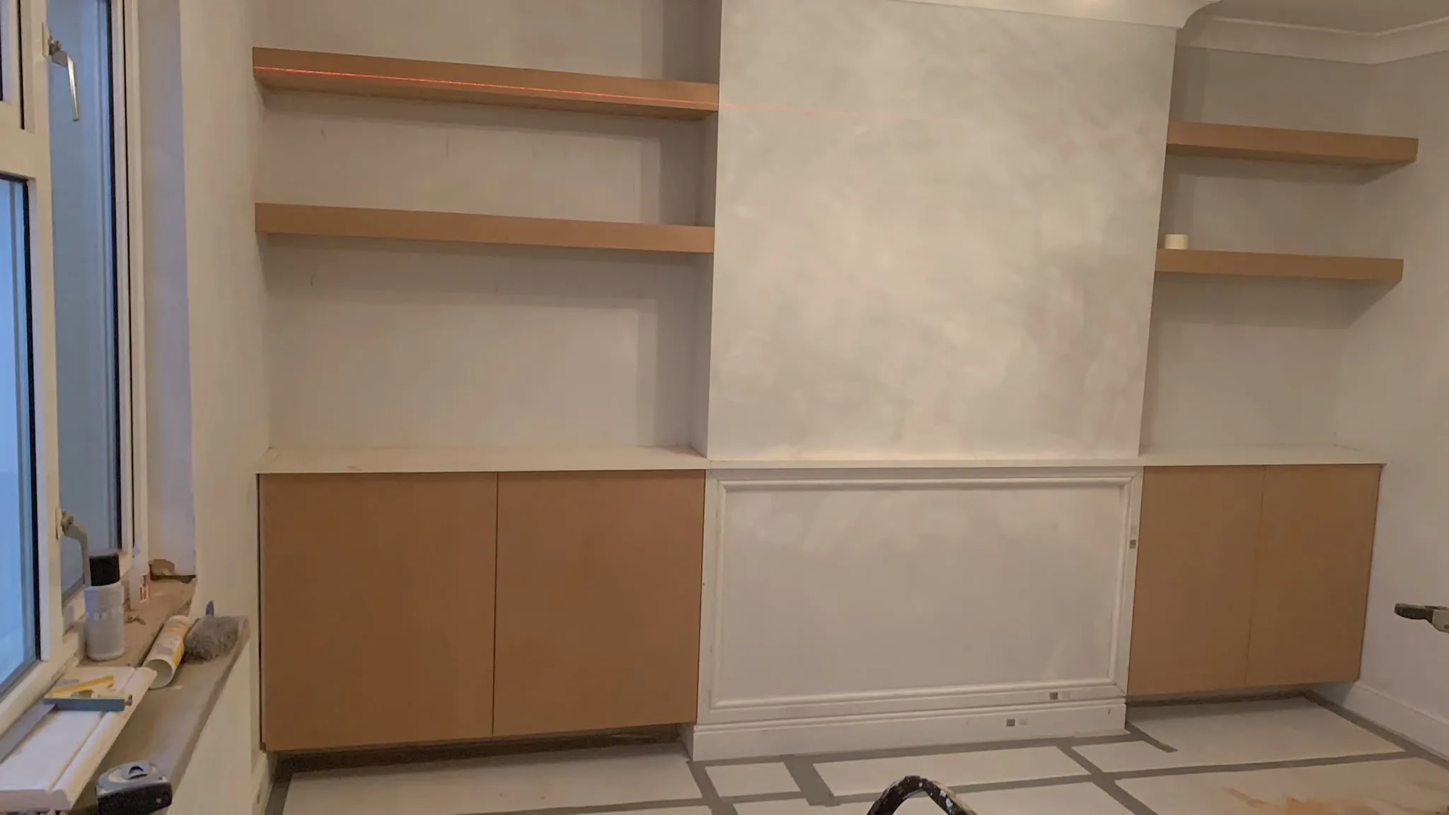 Custom wooden cabinetry installation with floating shelves in a modern interior